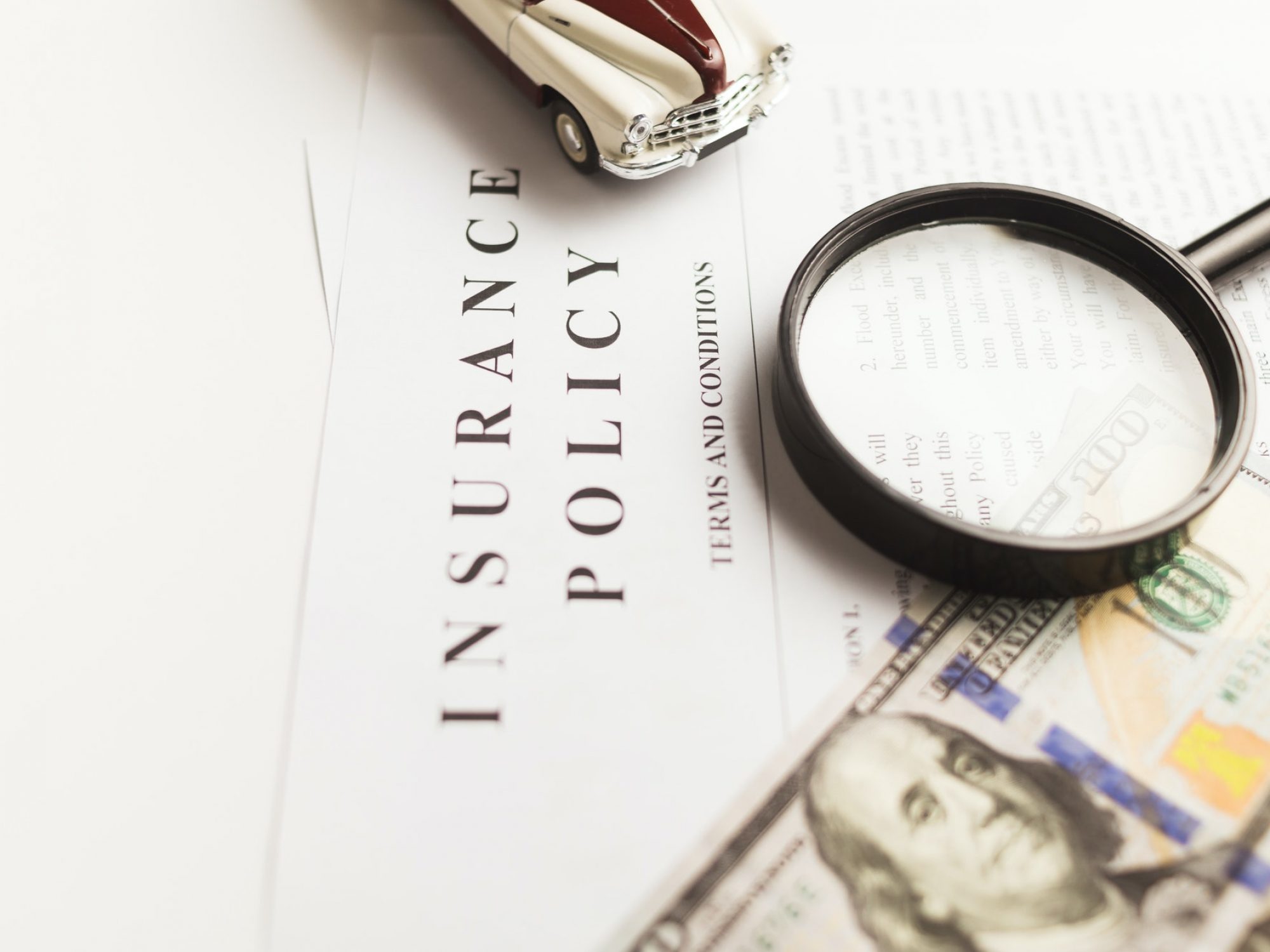 Certificate of motor insurance and policy with car and dollar bills.